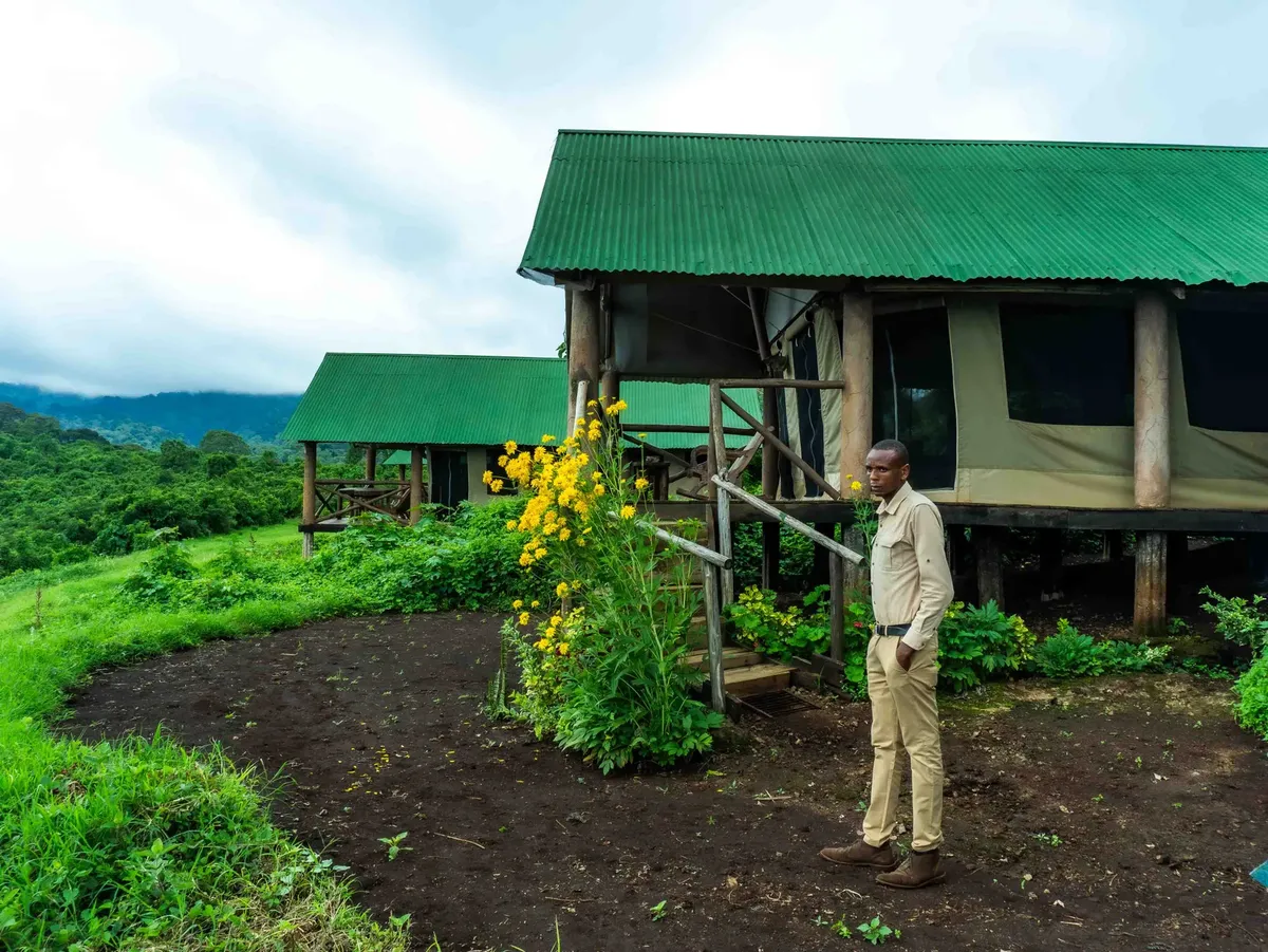A man stands outside a safari lodge surrounded by lush greenery in Arusha, Tanzania.